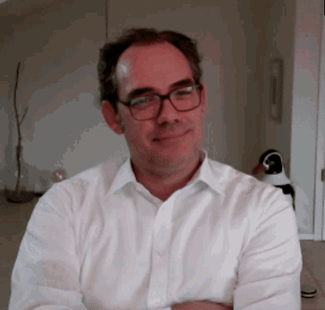 a man wearing glasses and a white shirt is smiling for the camera