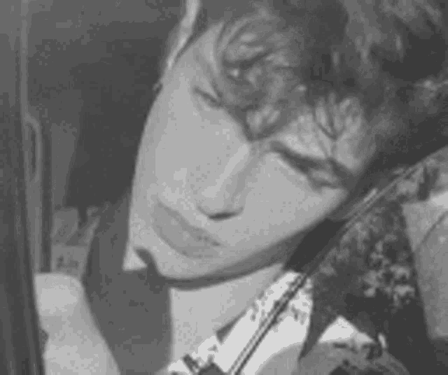 a black and white photo of a man playing a violin in a car .