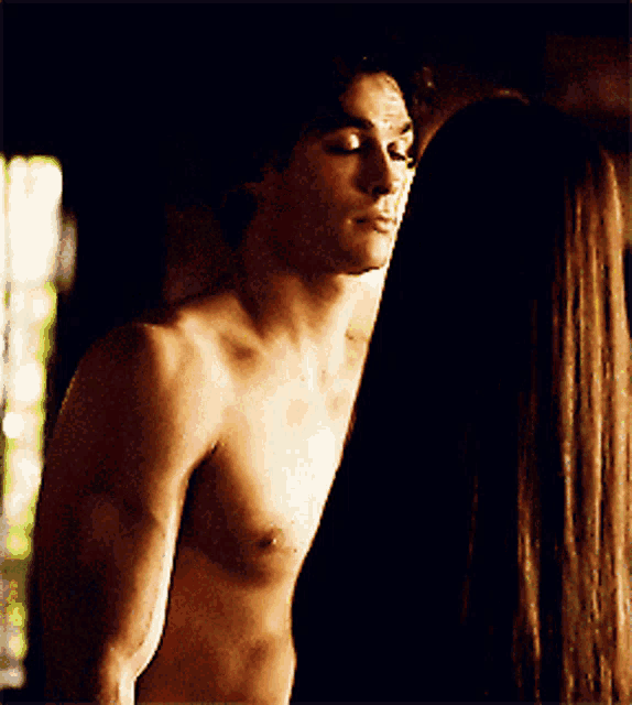 a man without a shirt is standing next to a woman with long hair