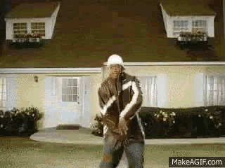 a man is dancing in front of a house with makeagif.com in the corner