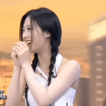 a woman with pigtails is smiling and laughing while holding her hands together .