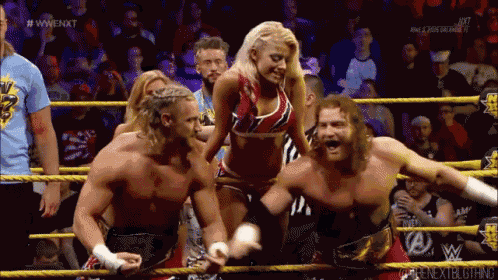 a group of wrestlers are standing in a ring and one of them is wearing a red and blue top