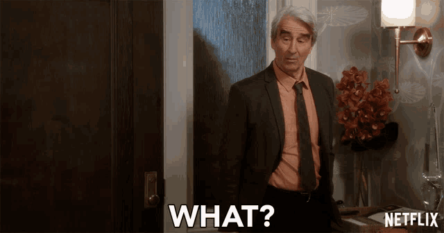 a man in a suit and tie says what in front of a netflix sign