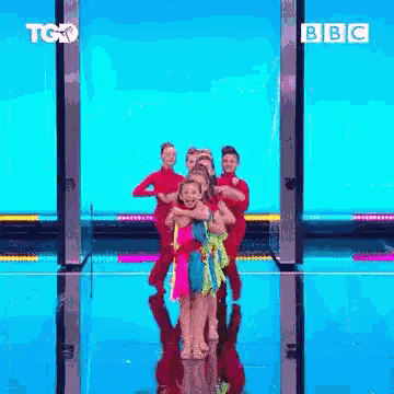 a group of young girls are dancing on a stage in front of a blue background .