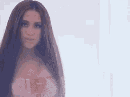 a woman with long brown hair is standing in front of a white wall .