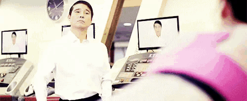 a man is standing in front of a treadmill in a gym while a woman is running on a treadmill .