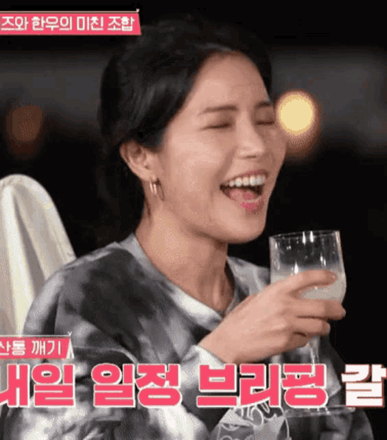 a woman in a tie dye shirt is holding a glass of milk and smiling .