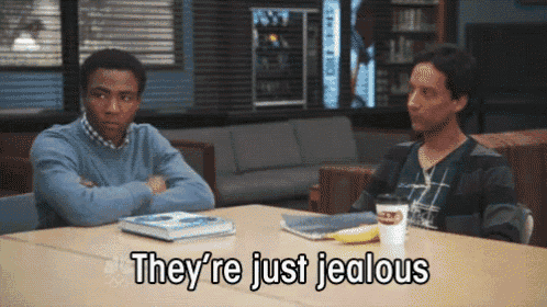 two men are sitting at a table with the words they 're just jealous above them