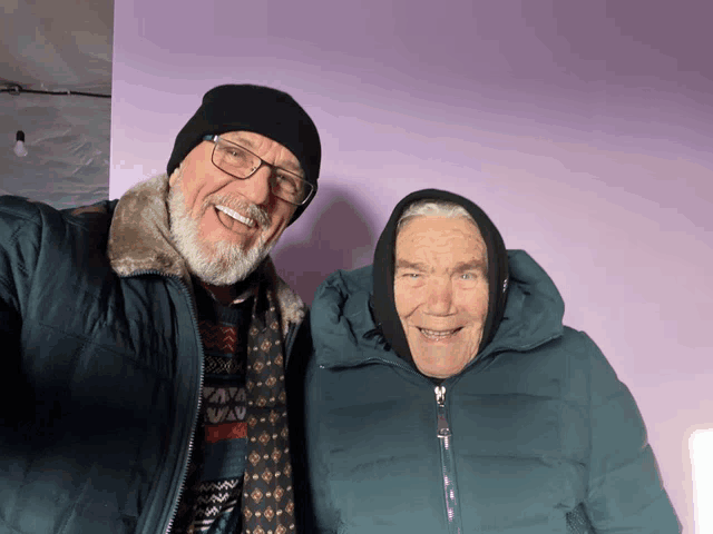 a man and a woman are posing for a picture and the woman is wearing a scarf around her head