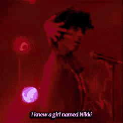 a man singing into a microphone with the words " i knew a girl named nikki " above him