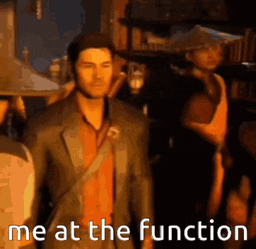 a man in a suit is standing in front of a group of people and says me at the function