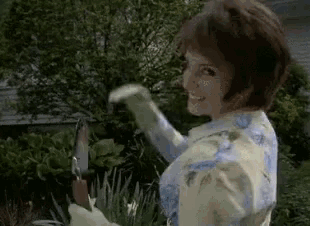 a woman in a blue and white floral dress is holding a shovel