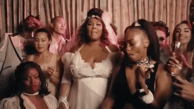 a woman in a wedding dress is dancing in front of a crowd of people at a party .