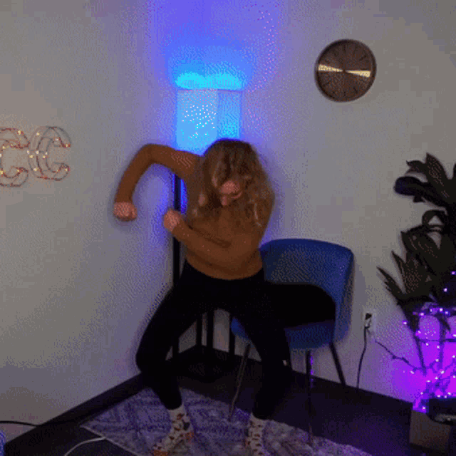 a woman is dancing in a room with a lamp and a clock on the wall