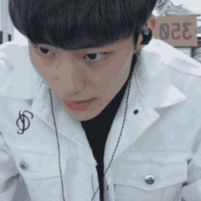 a man wearing headphones and a white jacket has a sticker on his jacket that says $