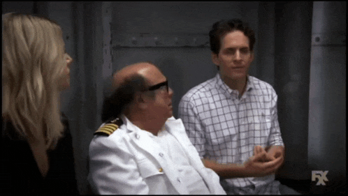 a man in a military uniform is talking to a woman and another man