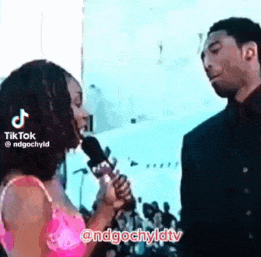 a woman is holding a microphone while talking to a man .