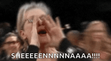 a woman is screaming in a crowd of people while holding her hands to her face .