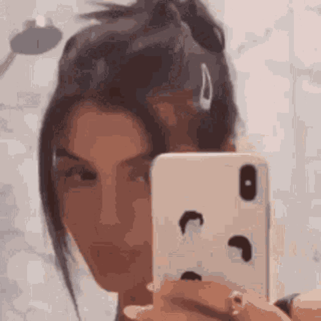 a woman is taking a selfie with her phone in a mirror .