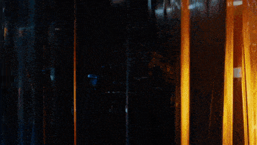 a man in a dark room with a reflection of himself in a glass door
