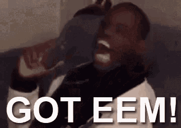 a man is sitting on a couch holding a bottle of beer and screaming .