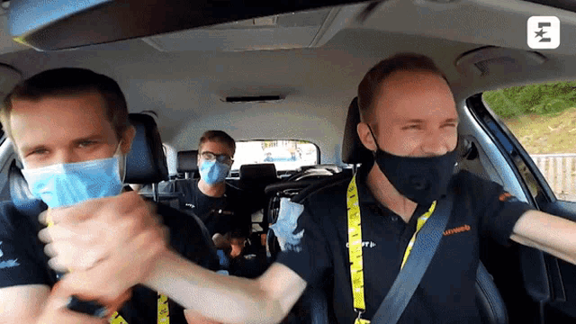 three men wearing face masks are sitting in a car with the letters lk on the roof
