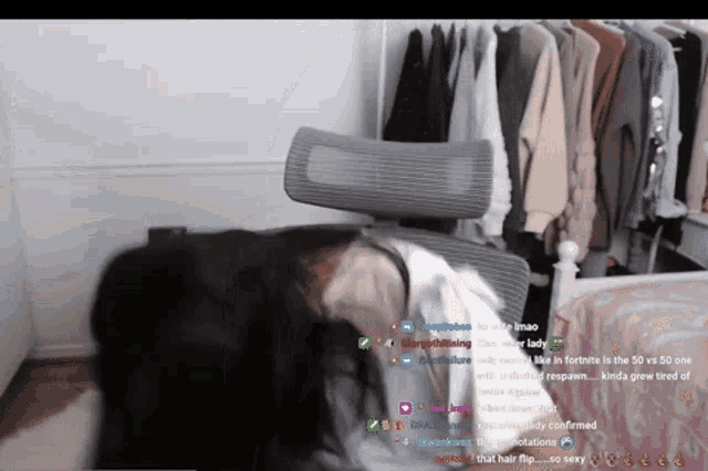 a woman is sitting in a chair in front of a closet full of clothes ..