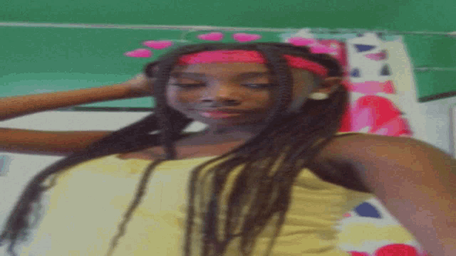 a girl with long braids and a pink headband with hearts on it