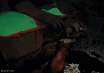 a man is laying on the floor with his mouth open and a green and orange blanket on his back ..
