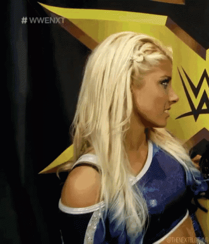 a woman with blonde hair is standing in front of a wwe sign .