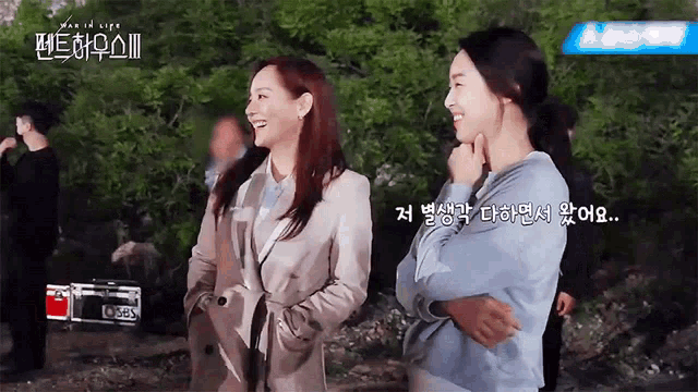 two women are standing next to each other and smiling while talking to each other .