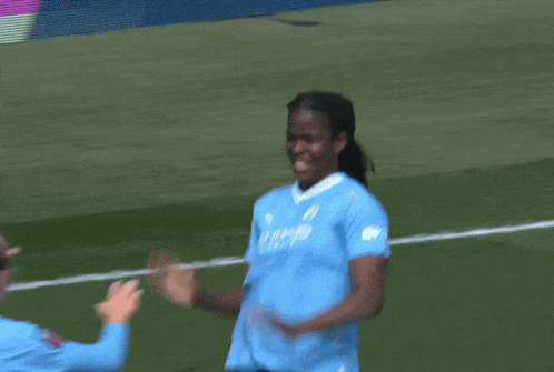 two female soccer players high five each other in a field