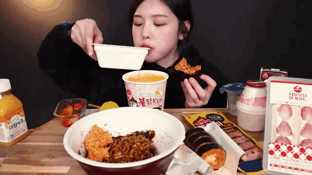 a woman is sitting at a table eating a bowl of food and a cup of soup