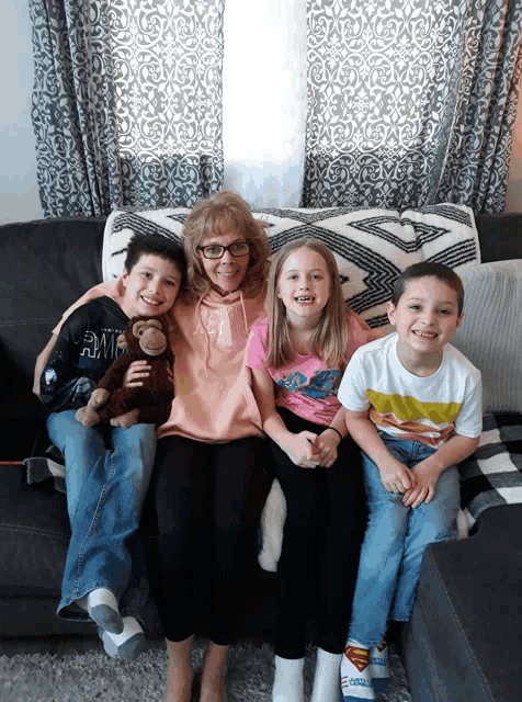 a woman sits on a couch with three children and a stuffed monkey
