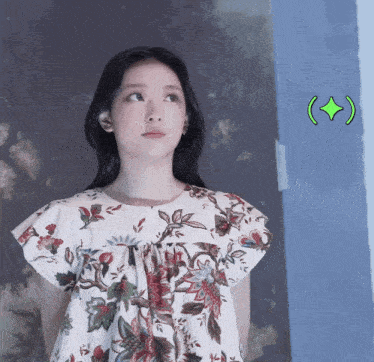 a woman wearing a floral dress has a green diamond in the corner