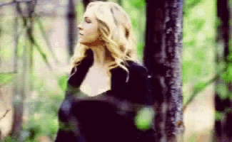 a woman is standing in a forest with her eyes closed .