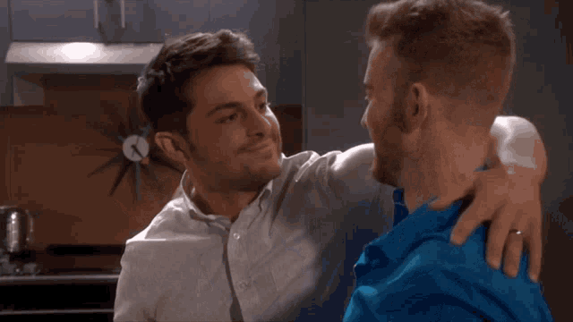 a man in a blue shirt is hugging another man