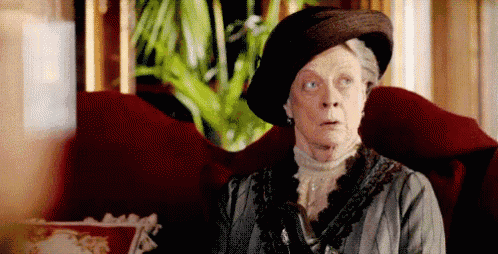 a woman wearing a hat and a dress is sitting in a chair .