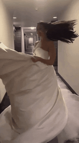 a woman in a white dress is holding a white pillow