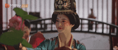 a woman in a traditional costume is standing in front of a tv screen