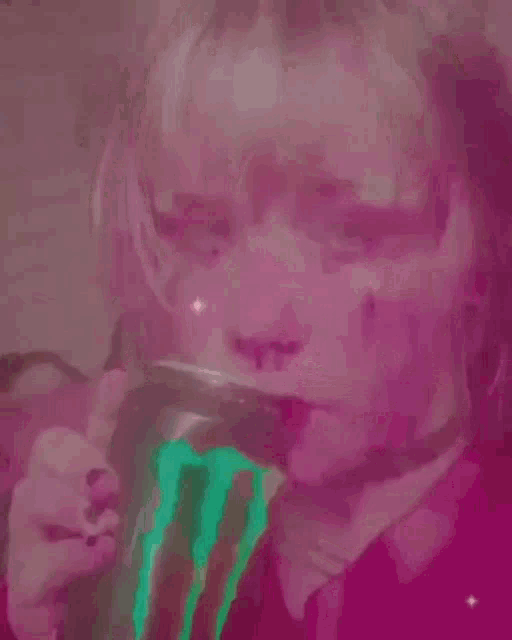 a woman is drinking from a cup with a green liquid coming out of her mouth