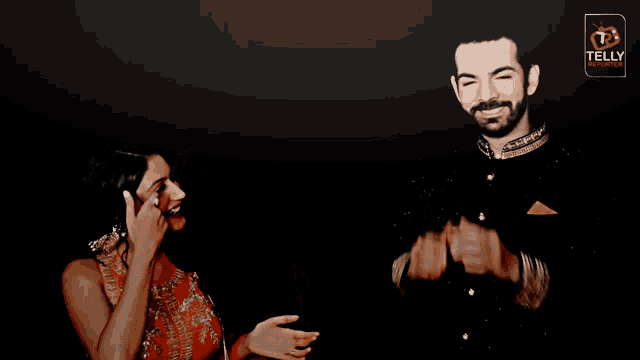 a man covering his face with his hands while a woman laughs in front of a tet logo