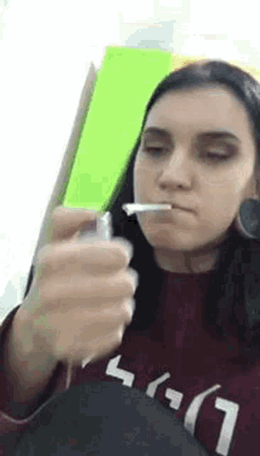 a woman is brushing her teeth with a toothbrush while wearing a red sweater .