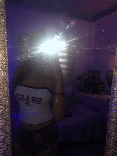 a woman taking a selfie in front of a mirror with a crop top that says abercrombie