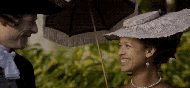 a man and a woman are standing under an umbrella and smiling at each other