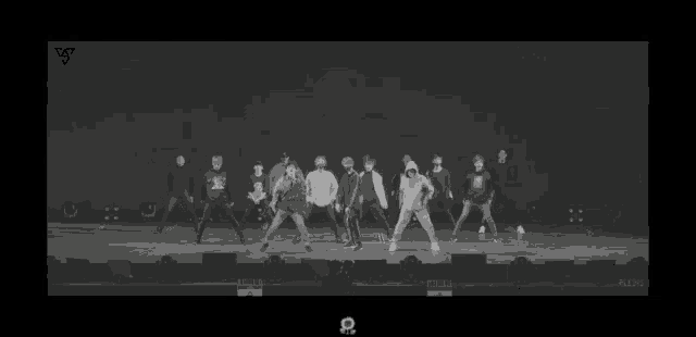 a group of people are dancing on a stage in front of a black background .