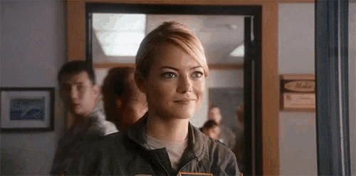a woman in a military uniform is standing in a room looking out a window .