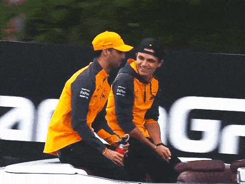 two men are sitting on the hood of a car .