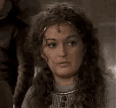 a woman with long curly hair is making a funny face and has the word epoustouflée on her face .