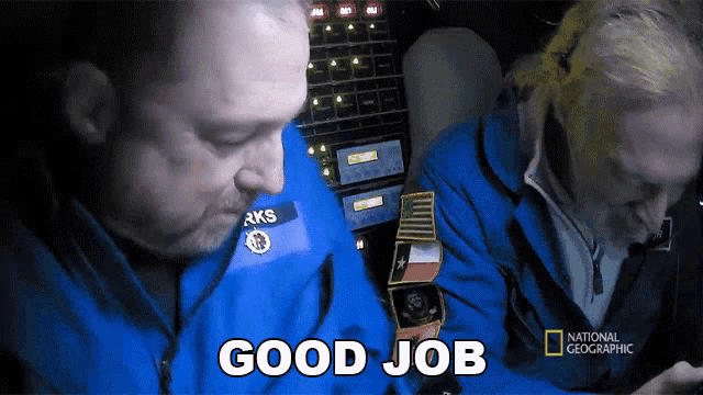 a man in a blue jacket says good job in front of a keyboard